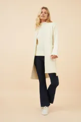 Saco largo tejido en lana color marrón claro con rayas verticales en crudo, con bolsillos laterales y solapas anchas.