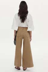 Blusa de mezcla de algodón y lino color blanco, con mangas abullonadas y cierre frontal de botones. Presenta detalles de bordado geométrico a cuadros en el cuello y los puños, y un gran bordado floral en el pecho.