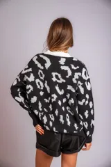Buzo de punto color negro con estampado animal print en gris claro, de corte holgado y manga larga.