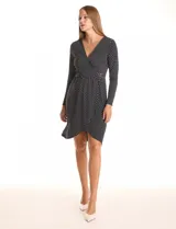 Vestido envolvente de seda fría estampado en blanco y negro, marca Luxology. Presenta escote en V cruzado, cintura elastizada con apliques metálicos en el lateral, manga larga entallada y ruedo asimétrico en el frente.