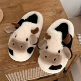 Pantuflas de peluche con diseño de vaca, confeccionadas en piel sintética suave. Cuentan con suela de goma antideslizante y diseño abierto en el talón.