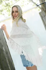 Poncho de tejido de algodón color beige claro, con diseño de punto calado y flecos en el borde inferior.