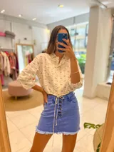 Minifalda de jean azul con botones frontales y ruedo desflecado.