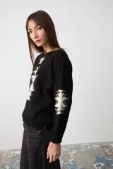 Sweater de punto negro con diseño geométrico en color crema en el frente y las mangas, de corte holgado y cuello redondo.