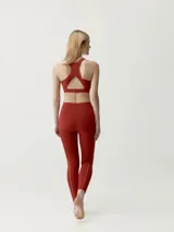 Calza deportiva roja con detalles de costuras y líneas laterales en tono contrastante.