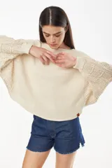 Sweater cropped de punto calado, color celeste melange, con mangas anchas de diseño holgado y cuello redondo.