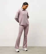 Buzo deportivo de corte oversized color lila, con cuello polo y cierre frontal con botones a presión. Presenta mangas largas con puños ajustados y una estampa bordada en el pecho. Confeccionado en una mezcla de poliéster, modal y elastano.