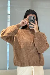 Buzo de tejido chenille color marrón, con cuello alto, mangas largas con puños elásticos y ruedo acanalado.