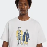 Remera de algodón color gris melange con cuello redondo y manga corta. Presenta un estampado frontal con dos figuras humanas vestidas con abrigos y bufandas en tonos amarillo, azul marino y gris.