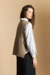 Chaleco de tejido de punto en color crema, con cuello alto y diseño acanalado. Presenta una silueta relajada con aberturas laterales.