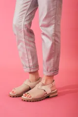 Sandalias de cuero con textura grabada, diseño de punta abierta y talón descubierto con tira ajustable. Poseen una suela de plataforma dentada en tono tierra.
