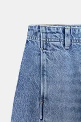 Jeans de tiro alto con corte barrel, pernera holgada que se estrecha hacia el tobillo y bajo deshilachado. Presenta costuras verticales decorativas en el frente y cierre frontal con cremallera y botón.