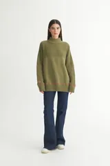 Buzo color verde oliva de punto con cuello alto, mangas largas y calce oversize.