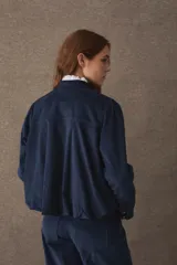 Chaqueta de corte corto y holgado, confeccionada en pana color marrón, con cuello mao, cierre frontal de botones dorados y mangas largas con puños rectos.