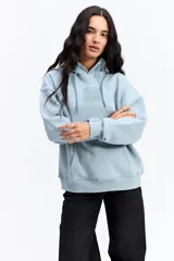 Canguro de algodón con capucha y bolsillo frontal, de diseño urbano y corte holgado. Presenta un parche rectangular en el pecho con detalles gráficos y el logo de la marca Mistral.