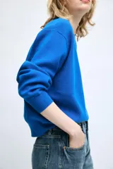 Jersey de punto color azul, con cuello redondo, manga larga y detalles de rib en cuello, puños y dobladillo.