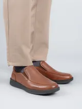 Zapato tipo slip on Hush Puppies de cuero color marrón, con suela negra de poliuretano con tecnología Spinal y plantilla Dual Fit.