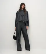 Pantalón wide leg de tiro alto confeccionado en denim de algodón. Presenta una pretina tipo sastrería con presillas, cierre frontal con botón y cremallera, bolsillos funcionales y nervaduras frontales que definen la silueta.