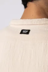 Camisa de manga larga confeccionada en tejido de lino con textura, de corte holgado y diseño versátil con cierre frontal de botones.