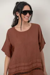 Blusa de lino color blanco, de corte amplio, con escote redondo, mangas cortas y detalle de guarda calada horizontal en la parte inferior.