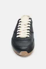 Championes de estilo running confeccionados en piel con textura granulada. Presentan detalles en contraste de color en el talón, cordones y lengüeta, con suela dentada de goma.