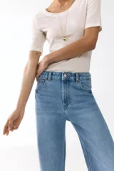 Jean de tiro alto con corte wide leg, confeccionado en denim de algodón con leve elasticidad. Presenta diseño clásico de cinco bolsillos, cierre frontal con botón y acabado en tono azul medio.