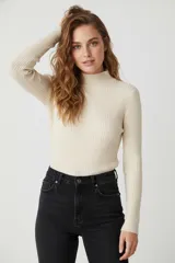 Polera de manga larga color beige claro, de tejido acanalado y cuello alto, de calce ajustado al cuerpo.