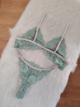 Conjunto de lencería compuesto por un bralette triangular y una bombacha tipo tanga, confeccionados en encaje color verde oliva con detalles y elásticos en tono tostado.