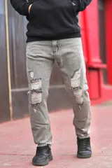 Pantalón mom jean de denim gris con roturas y efecto desgastado en las rodillas.