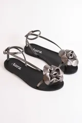Sandalias bajas color cuero con tiras finas y aplique de flor dorada.