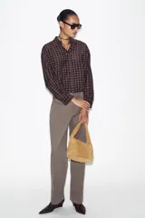 Pantalón recto color gris topo, de tiro medio, con bolsillos delanteros y falsos bolsillos de doble vivo en la espalda. Cierre frontal con cremallera, botón interior y ganchos.