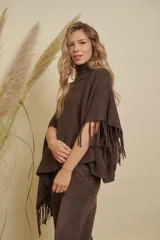 Poncho tejido de punto acanalado en color marrón chocolate, con cuello alto y diseño irregular con flecos en los bordes.