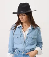 Sombrero de fieltro negro, estilo cowboy, con ala ancha y una fina cinta de cuero sintético con hebilla metálica dorada alrededor de la copa.