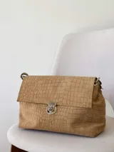 Cartera bandolera de cuero marrón con textura croco, solapa frontal, cierre metálico de giro plateado y correa de cadena con eslabones.