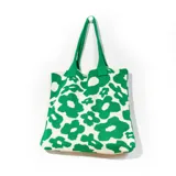 Bolso tipo tote de tejido de punto con estampado de flores grandes en color verde y blanco. Asas de hombro verdes.