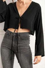 Blusa corta negra con escote en V y mangas largas acampanadas.