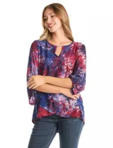 Blusa Ruby Rd. de corte holgado con diseño texturizado y estampado floral en tonos azul y bordó. Presenta cuello redondo con escote tipo keyhole y detalle metálico, mangas tres cuartos amplias y dobladillo asimétrico.