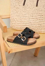 Sandalias negras de mujer con tiras cruzadas y hebillas metálicas doradas. Suela anatómica con detalle de corcho.