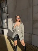 Blazer de corte entallado con diseño a rayas verticales, cuello solapa y cierre frontal de tres botones. Presenta mangas largas y un diseño asimétrico en el ruedo.