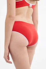 Bombacha tipo bikini de microfibra sin costuras, color rojo con detalles en blanco en los bordes. Presenta un diseño de tiro medio con logo pequeño bordado en el lateral.