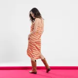 Vestido corto con estampado geométrico en tonos naranja, rosa y marrón. Tiene cuello halter y espalda descubierta.