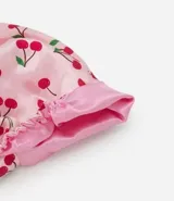 Gorro de satén antifrizz de la marca Alchemia, color rosado con estampado de cerezas rojas. Viene en una caja con diseño a juego.