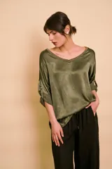 Blusa holgada de satén color beige, con escote en V y mangas largas con trabilla para sujetar remangadas.