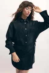 Vestido camisero negro con sobrefalda integrada, botones de nácar y estampado con leve rugosidad.
