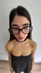 Vestido corto negro con estampado de lunares blancos, escote recto y breteles finos, con detalle de choker incorporado en el mismo estampado.