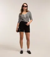 Bermuda femenina de tejido plano crepé, color negro, con trabillas en la cintura y cierre delantero. Presenta bolsillos falsos.