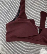 Top de bikini color bordó, con breteles anchos y abertura triangular en el centro del busto. Se ata en la espalda y tiene copas desmontables.