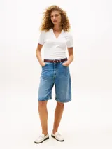 Chomba blanca de corte slim fit con cuello polo abierto y mangas cortas con ribetes en azul y rojo. Presenta logo de Tommy Hilfiger bordado en el pecho.