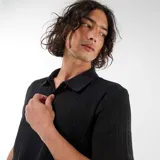 Remera de punto calado negro, de manga corta, con cuello polo y diseño texturizado.
