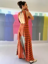 Vestido largo de lino rayado color naranja y marrón, con escote en V y espalda descubierta. La falda es amplia y con mucho movimiento.